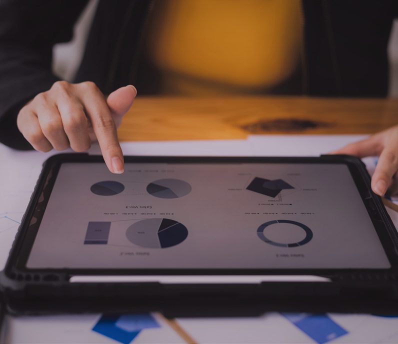 Businesswoman analyzing financial statistics displayed on the tablet screen, working data document graph chart report marketing research development planning management strategy accounting.